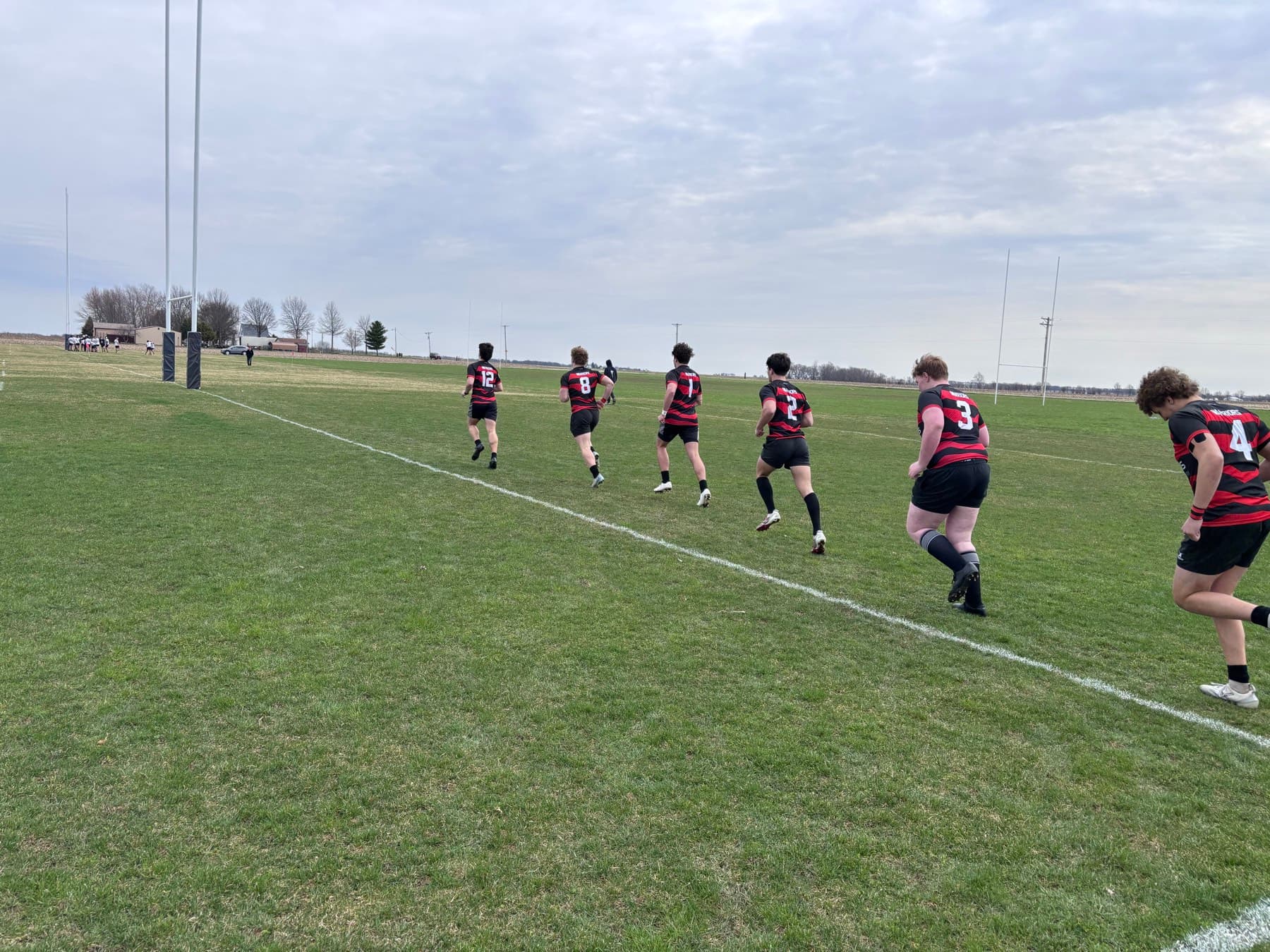 Fortivus players running upfield on a wide grass pitch